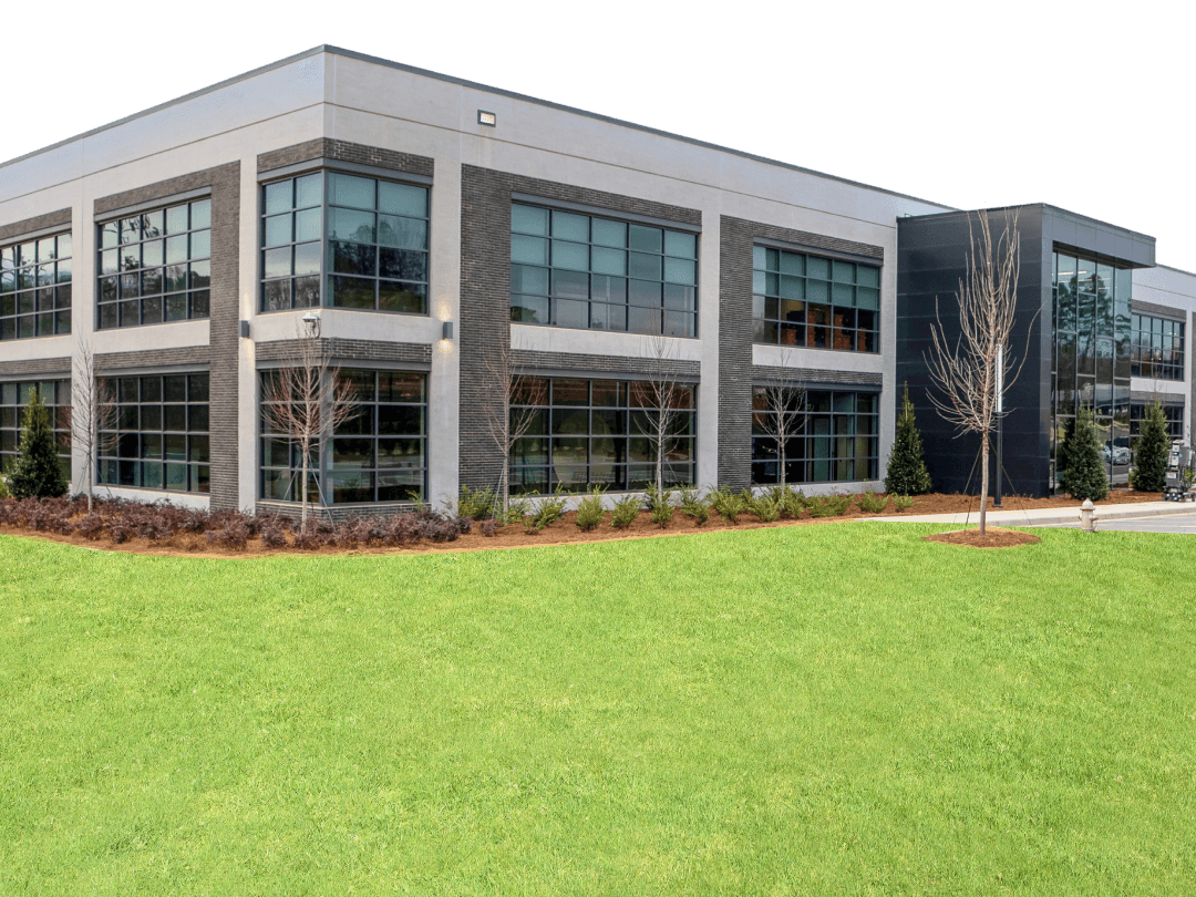 Modern Commercial Building Front Exterior View Two-story modern commercial office building with large glass windows, dark brick facade, and landscaped lawn in front.