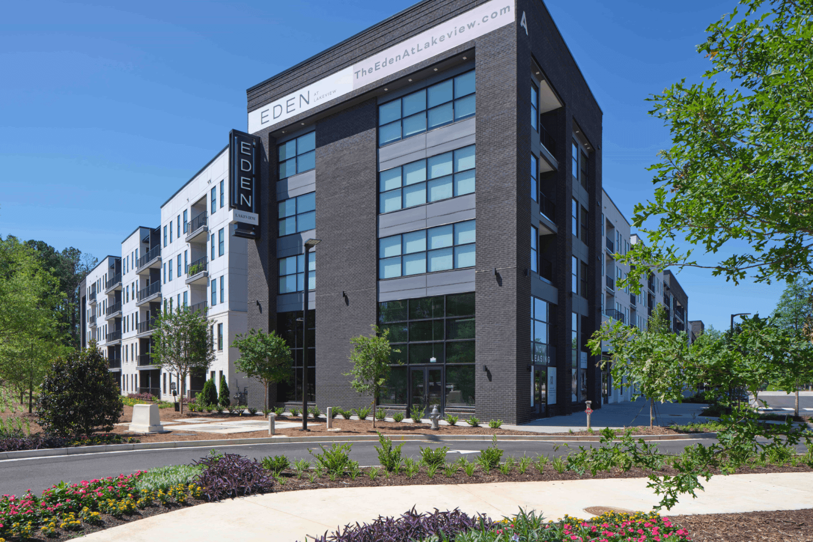 Eden at Lakeview Modern Apartment Building Exterior Modern multi-story Eden at Lakeview apartment building with dark brick, white panels, large windows, and landscaped gardens in front.