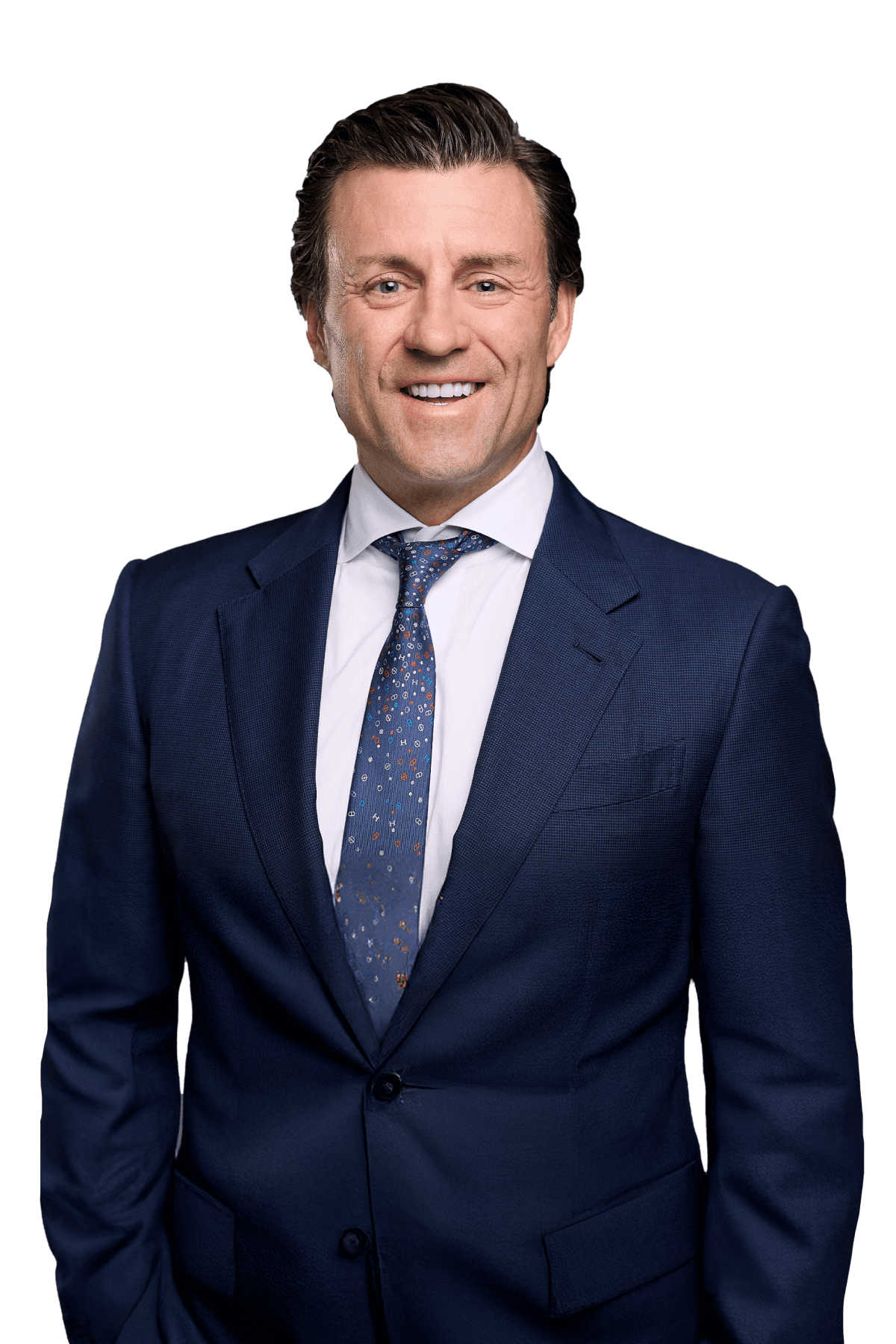 Professional headshot of Nathan Pramik wearing a navy blue suit with patterned tie, smiling against white background