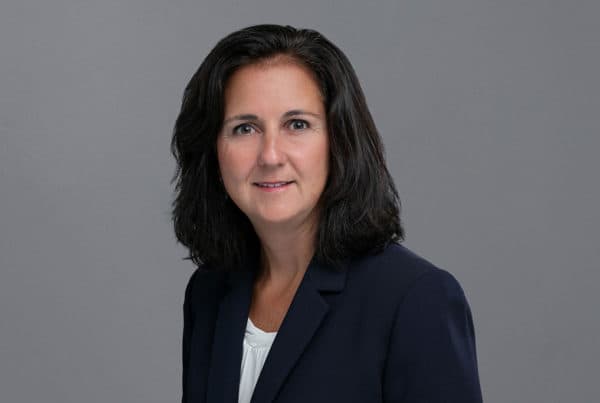 Professional headshot of D. Richwine wearing a navy blazer and white top against a gray background
